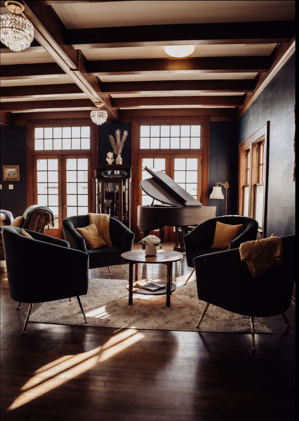 A circle of velvet chairs around a small table in the sunlit parlor at the Abbey at Otter Creek, with a grand piano behind them