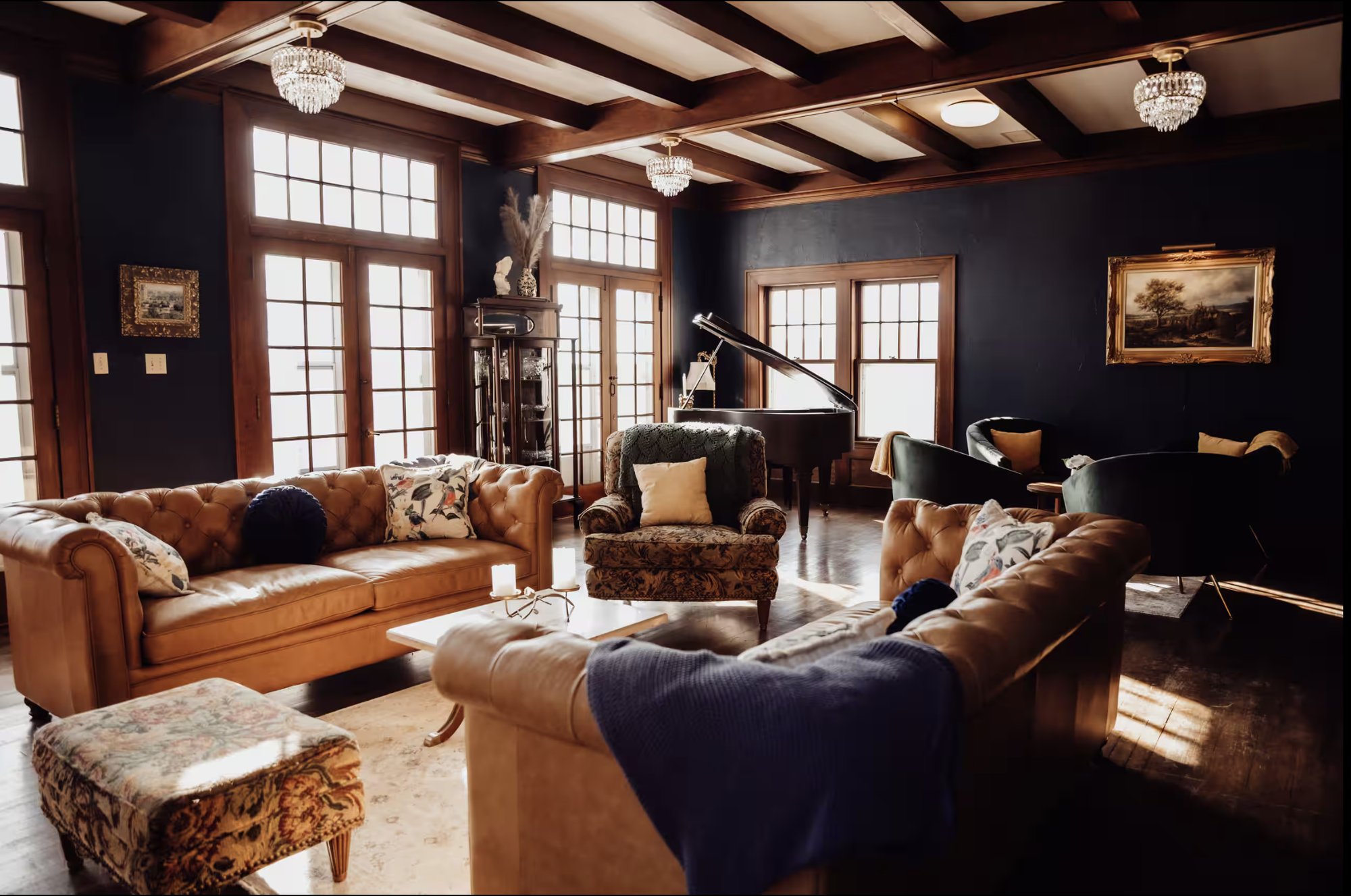The Abbey's parlor with leather sofas, crystal chandeliers, tall windows and a grand piano